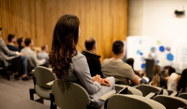 young-woman-sitting-in-audience-on-conference-or-w-2026-01-08-02-41-01-utc-2